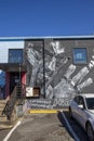 A black and white wall mural of MF Doom on the side of a brick building in Little Five Points surrounded by parked cars