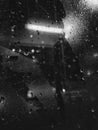Black and white water drops on the window, evening lights, raining mood Royalty Free Stock Photo