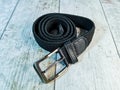 Black wicker trouser belt with a silver buckle on a wooden tabletop background