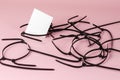 Black wire ties and white abstract geometric shapes on a pink background. Old cut plastic ties randomly on colored background