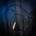 Black wired earphone in dark background. Earphones with a tangled wire. Royalty Free Stock Photo