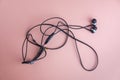 Black wired earphones, isolated on pink background