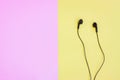 Black wired earphones on pink and yellow background Royalty Free Stock Photo