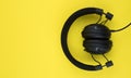 Black wired headphones on a yellow background. Overhead, isolated professional-grade headphones for DJs and musicians Royalty Free Stock Photo