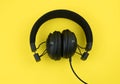 Black wired headphones on a yellow background. Overhead, isolated professional-grade headphones for DJs and musicians Royalty Free Stock Photo