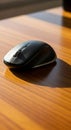 A black wireless computer mouse rests on a wooden surface. The mouse has a sleek Royalty Free Stock Photo