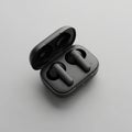Black wireless earbuds in an open charging case placed on a neutral Royalty Free Stock Photo