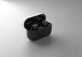 Black wireless earbuds rest inside an open charging case. The case has a two-tone design with a Royalty Free Stock Photo