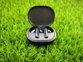 Black wireless headphones in a box on a grass background
