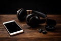 Black wireless headphones and mobile phone on dark wooden background Royalty Free Stock Photo