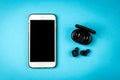 Black wireless headphones and white mobile phone on blue background Royalty Free Stock Photo