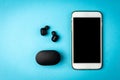 Black wireless headphones and white mobile phone on blue background Royalty Free Stock Photo