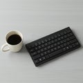 A black wireless keyboard is placed on a light gray surface alongside a white ceramic Royalty Free Stock Photo