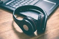 Black Wireless Overhead Headphones Lying On The Corner Of A Laptop Keyboard In An Office