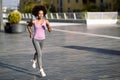 Black woman, afro hairstyle, running outdoors in urban road. Royalty Free Stock Photo