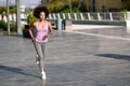 Black woman, afro hairstyle, running outdoors in urban road. Royalty Free Stock Photo