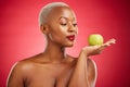 Black woman, apple and thinking for natural nutrition or healthy diet against a red studio background. African female