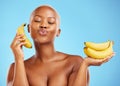 Black woman, banana and diet for potassium, vitamin or fiber against a blue studio background. Face of calm African