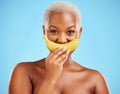 Black woman, banana and mouth for potassium, vitamin or fiber against a blue studio background. Portrait of happy