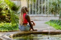 Black woman with blonde braids sitting near a small fountain looking up Royalty Free Stock Photo