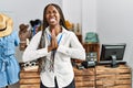 Black woman with braids working as manager at retail boutique begging and praying with hands together with hope expression on face