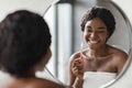 Black woman brushing her teeth and smiling in the bathroom Royalty Free Stock Photo