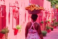 A black woman carries a bowl of bananas on her head. Street seller of bananas. Pink Alley.