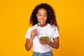 Black woman in casual holds bowl of vegetable salad, studio Royalty Free Stock Photo