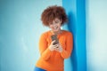 Black woman, cellphone and laughing on mobile on blue wall of social media, technology or network. Happy young girl Royalty Free Stock Photo