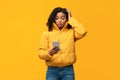 Black Woman With Cellphone Reading Bad Message On Yellow Background