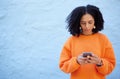 Black woman, cellphone and typing on blue background, wall or mockup. Female with mobile, technology and social media Royalty Free Stock Photo