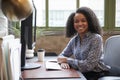 Black woman at a computer in an office smiling to camera Royalty Free Stock Photo