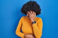 Black woman with curly hair standing over blue background with sad expression covering face with hands while crying Royalty Free Stock Photo