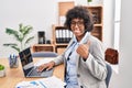 Black woman with curly hair wearing call center agent headset at the office doing happy thumbs up gesture with hand Royalty Free Stock Photo