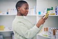 Black woman, customer and box on shelf for medication, pills or medicine at the pharmacy. African female person or