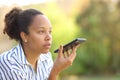 Black woman dictating text on phone in a garden Royalty Free Stock Photo