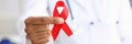 Black woman doctor holding a red ribbon