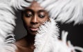 Black Woman Face with White Feather. Afro Beauty Model Face Skin Care and Cosmetics. Dark Skinned Women Fashion Portrait over Gray