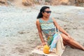 Black woman gazes at the horizon while having a picnic on the beach