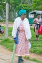 Black woman with green umbrella walking through Zulu village in Zululand, South Africa