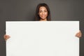 Black woman holding big white empty banner singboard on gray banner background Royalty Free Stock Photo