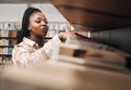 Black woman, library shelf and books for reading, student knowledge or education development at university. African