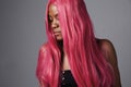 Black woman with long shiny straight pink hair.