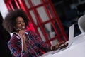 Black woman in modern office speeking on phone over earphones Royalty Free Stock Photo