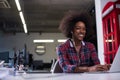 Black woman in modern office speeking on phone over earphones Royalty Free Stock Photo