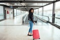 Black woman in the moving walkway at the airport with a pink sui Royalty Free Stock Photo