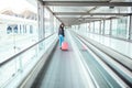 Black woman in the moving walkway at the airport with a pink sui Royalty Free Stock Photo