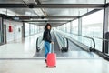 Black woman in the moving walkway at the airport with a pink sui Royalty Free Stock Photo
