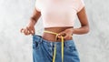 Black woman in old big jeans measuring her waist, showing results of slimming diet or liposuction, grey background Royalty Free Stock Photo