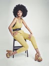 Black woman, portrait and relax on chair in fashion, yellow jumpsuit or high heels on a gray studio background. African Royalty Free Stock Photo